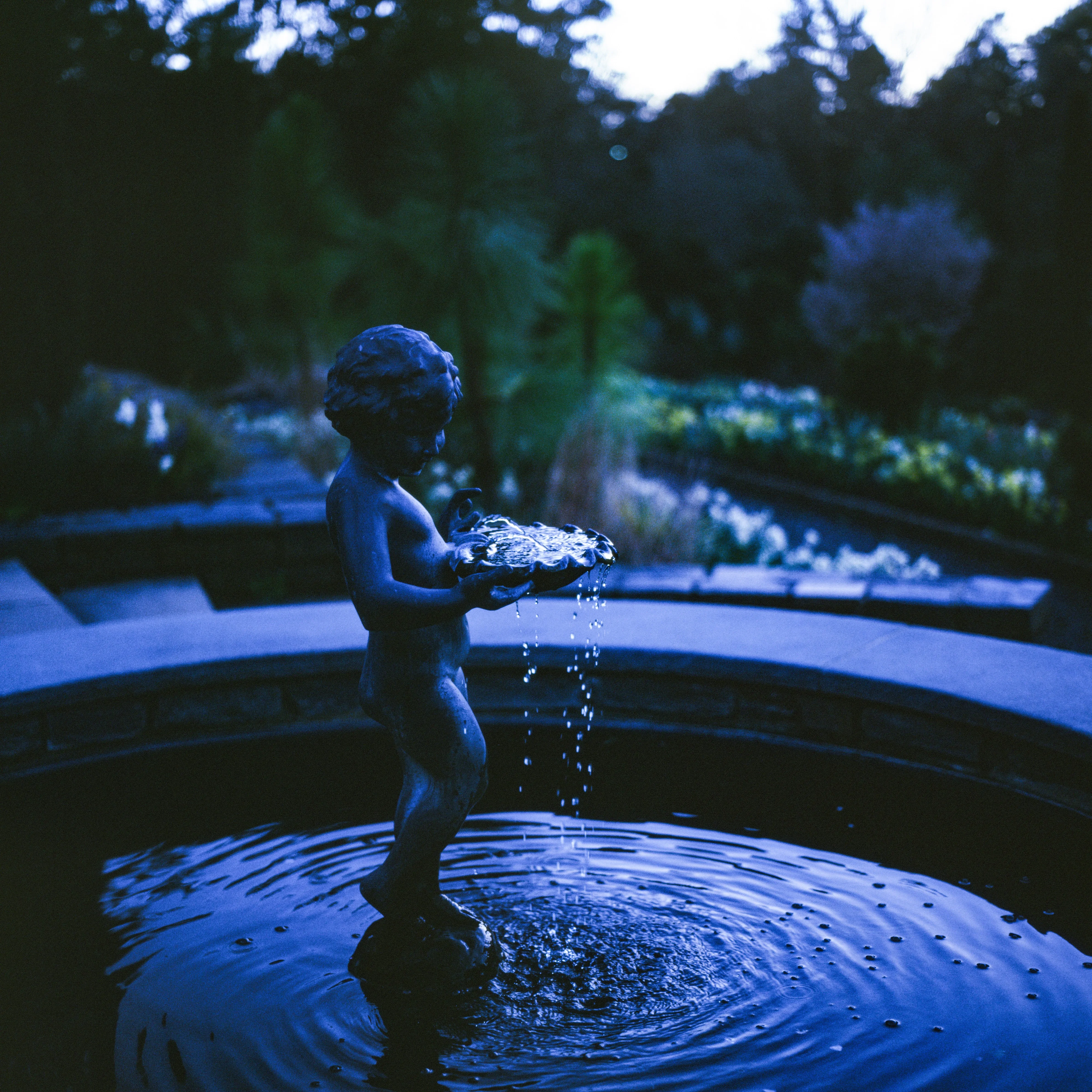 Cherub statue in fountain, twilight blue