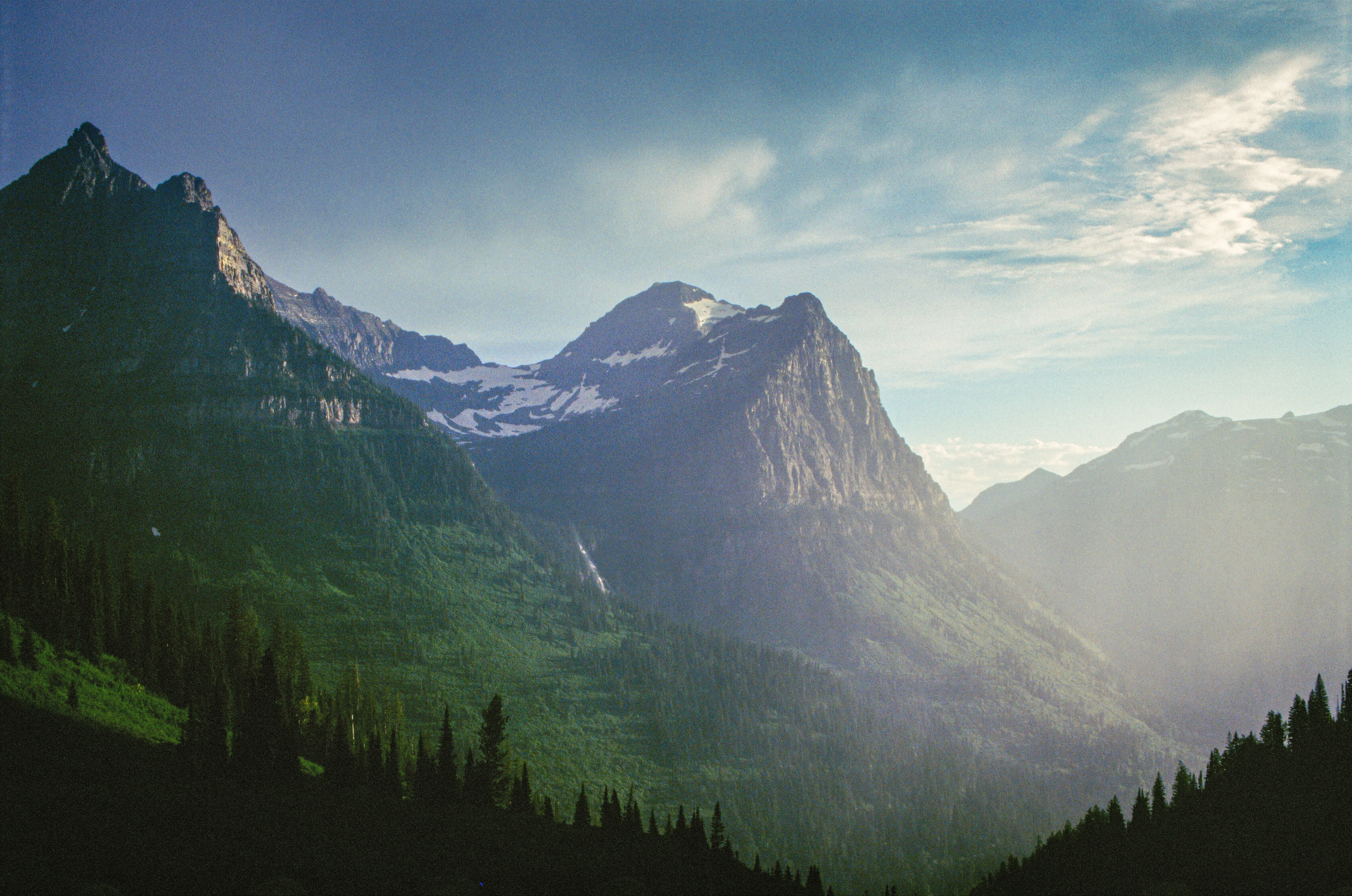 Sunbeams pouring into a hazy mountain valley, layered ridges