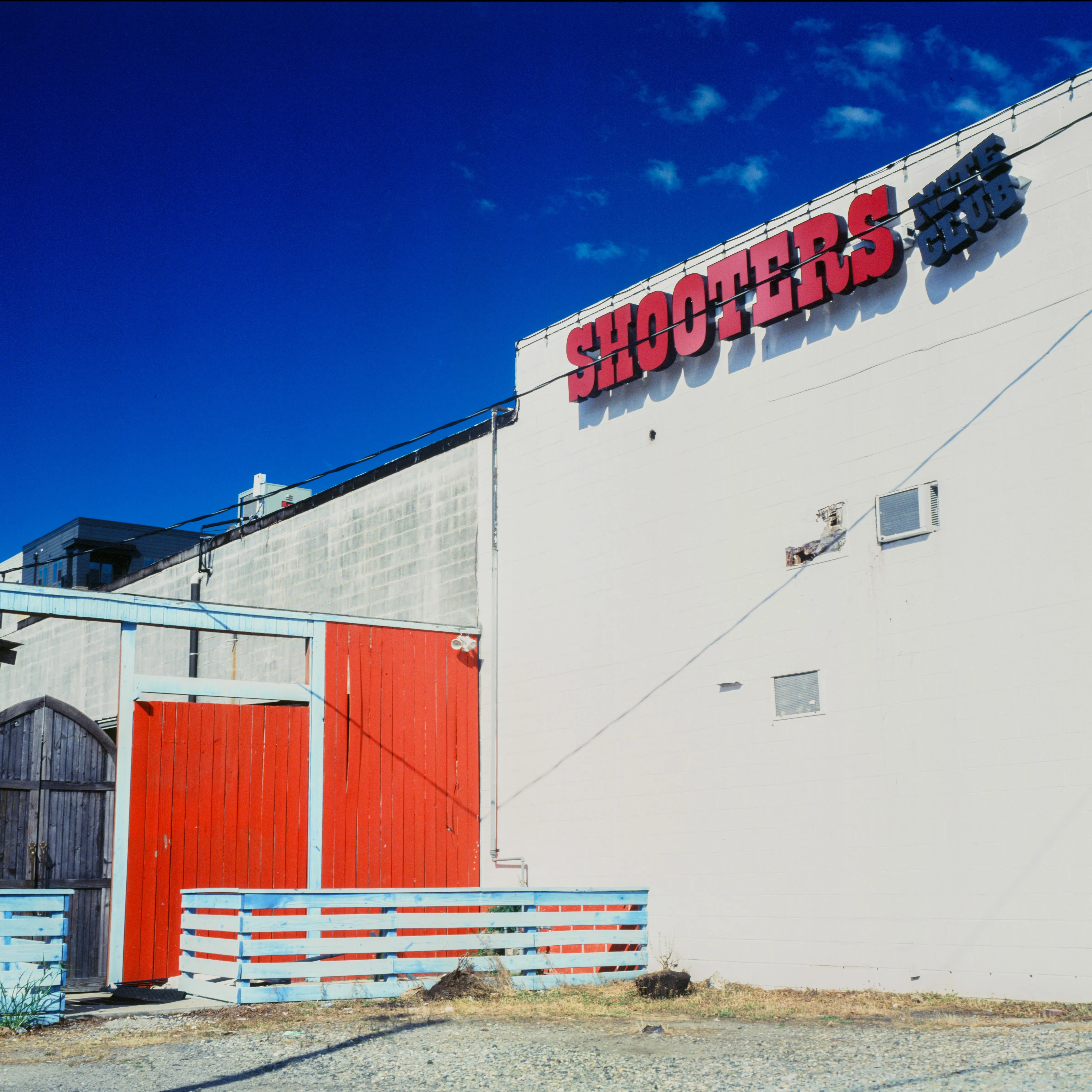 Shooters Saloon, vivid red sign and red door against bright white wall