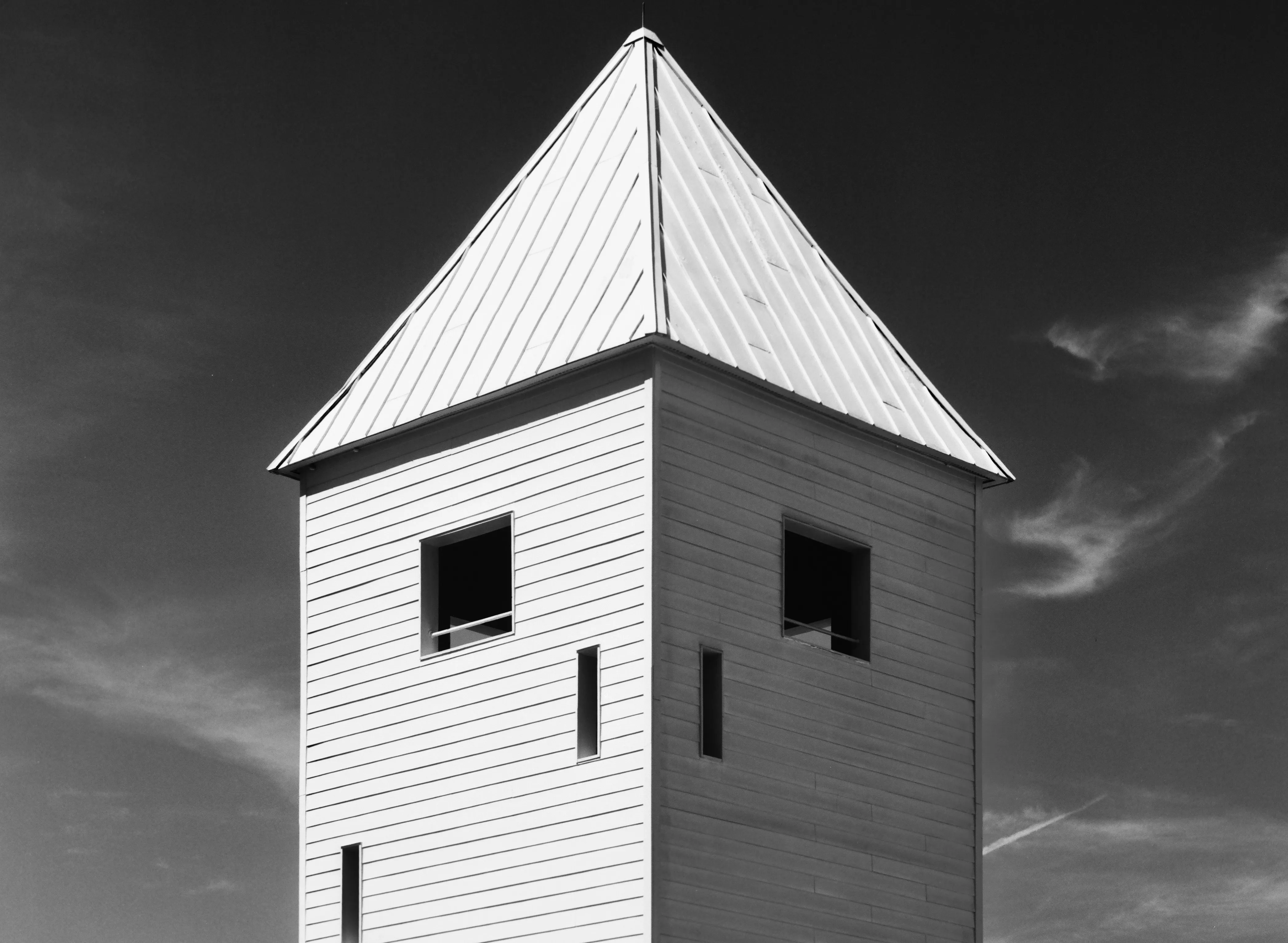 White clapboard tower with a pyramidal metal roof, black and white